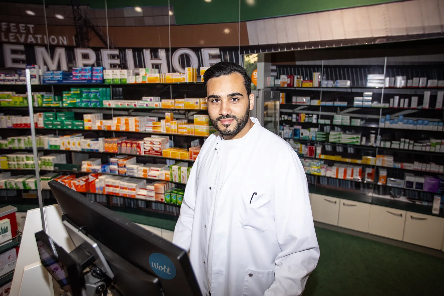 Mr Hani Ayade standing in front of the shelves of his pharmacy