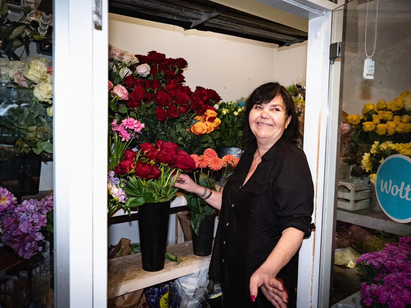Jaana Myrttinen at the door of her flower shop, buckets of blooms either side